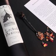 Gros plan sur l'étiquette de la bougie Locked Desires avec une chauve-souris dans une cage